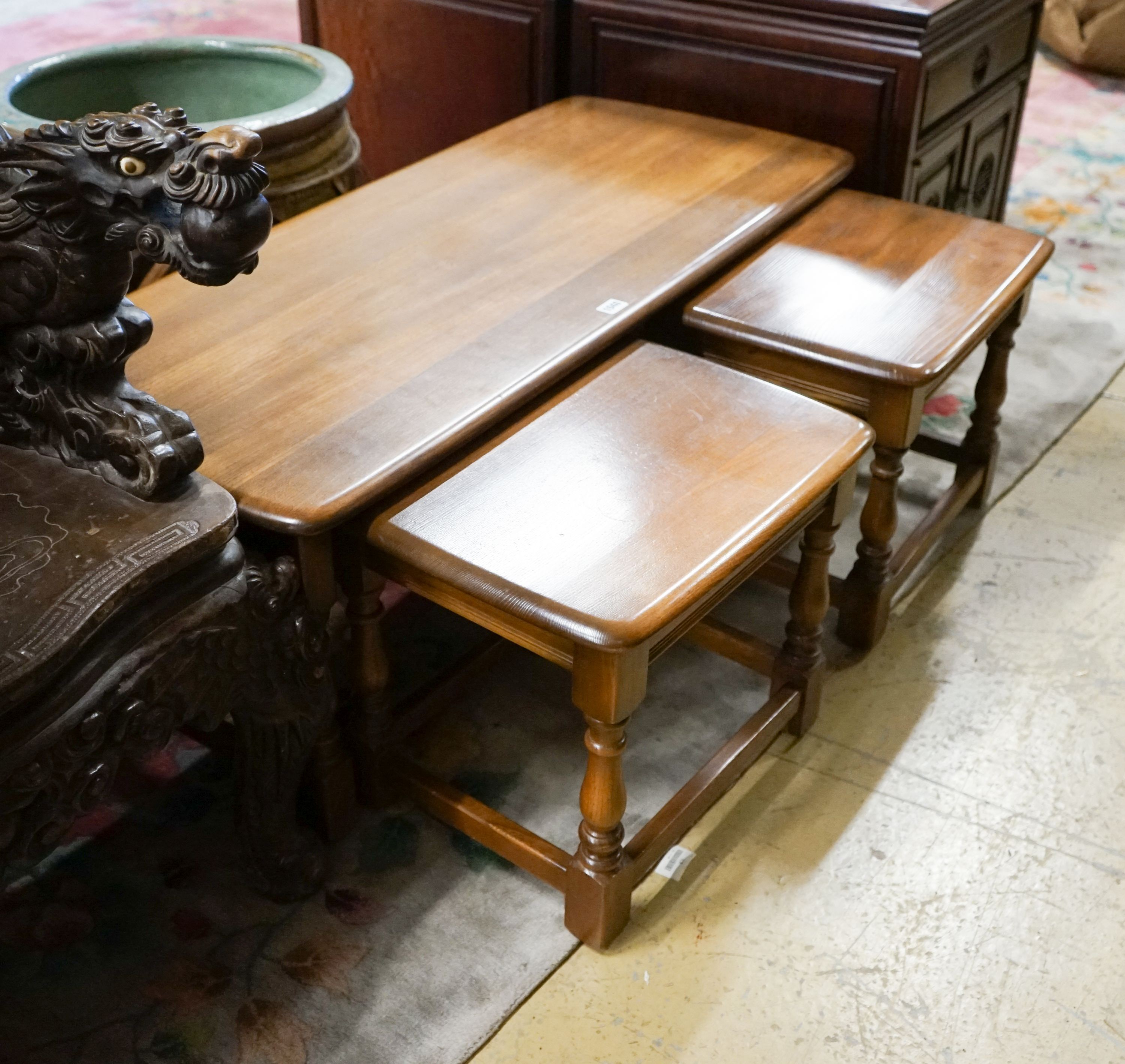 A nest of three Ercol elm tables, largest width 114cm, depth 49cm, height 41cm